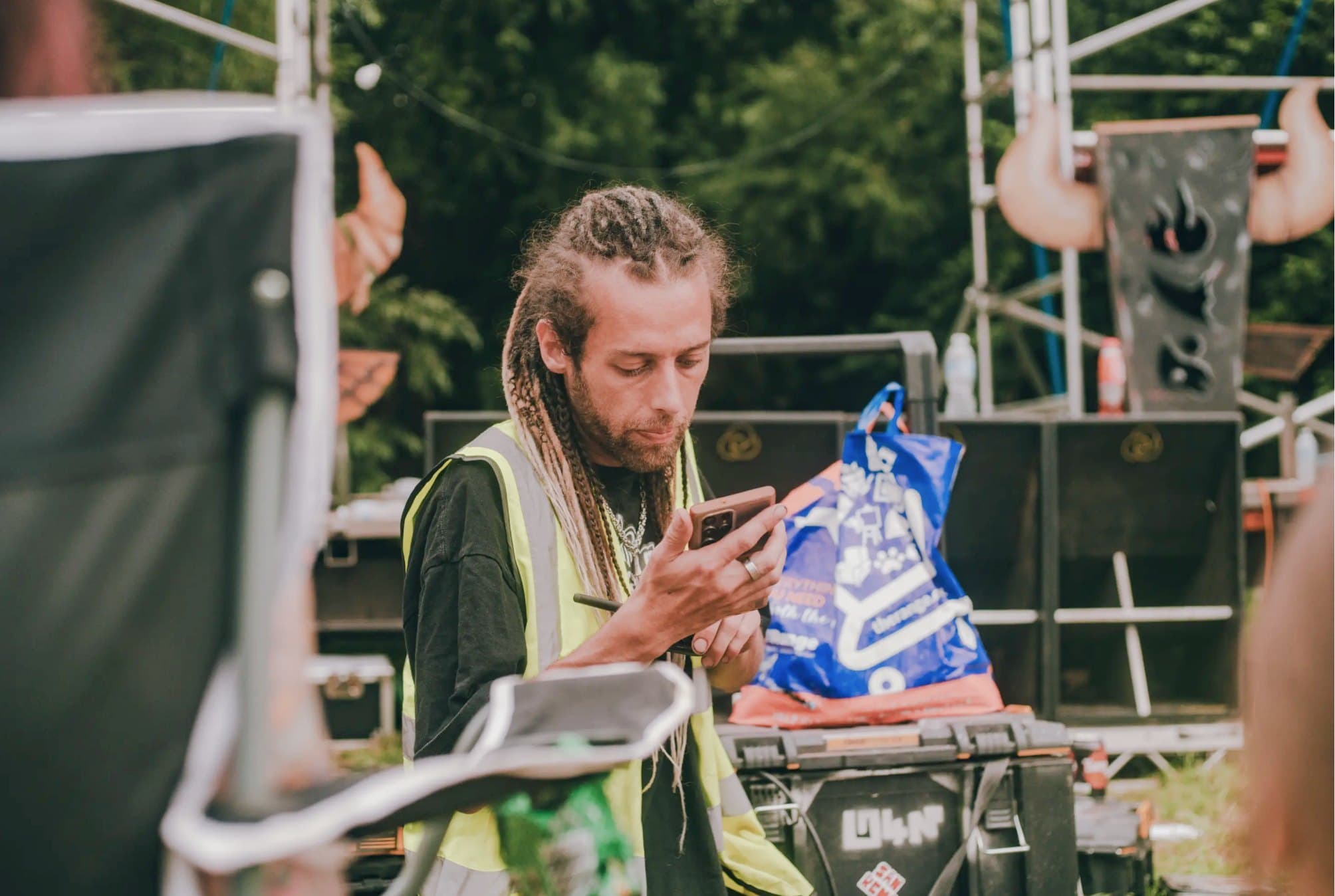 A crew member in a hi-vis vest checking the Lanyard app on their phone during the site build.