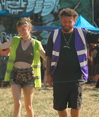 Alex and Abby walking through the festival in hi-vis, radio in hand