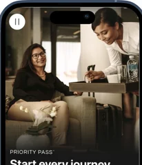 The Priority Pass app open on a phone, a lounge behind it
